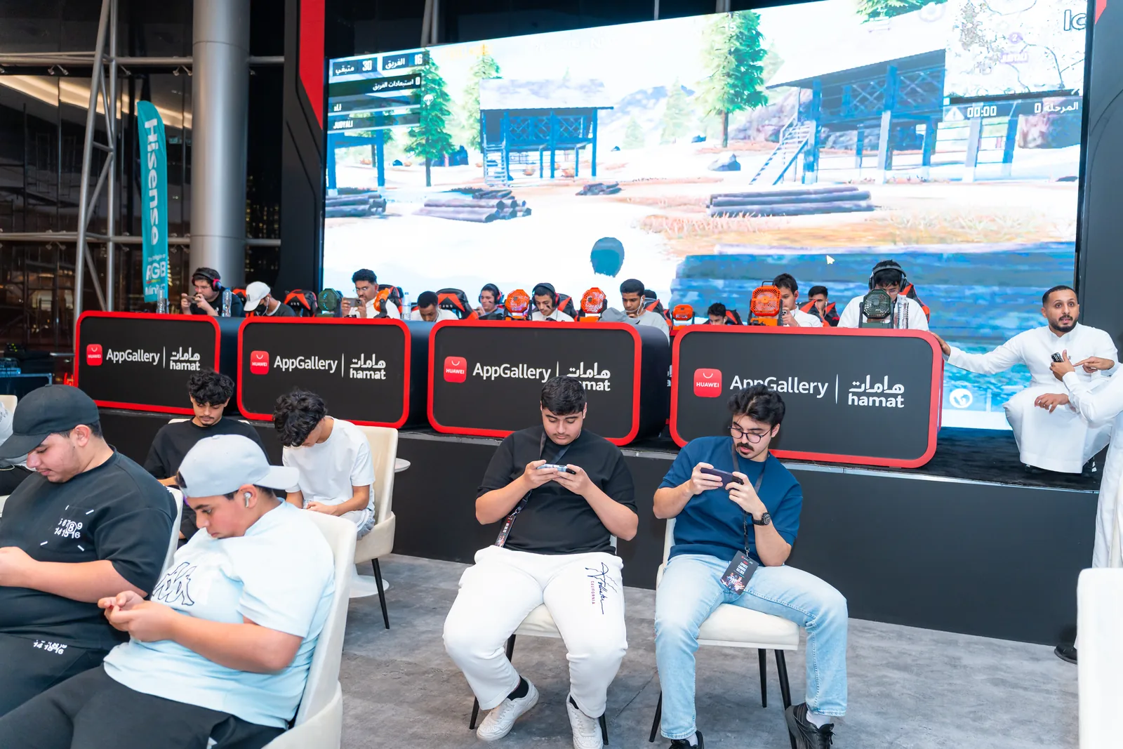 Players competing in a mobile tournament in front of the main event screen